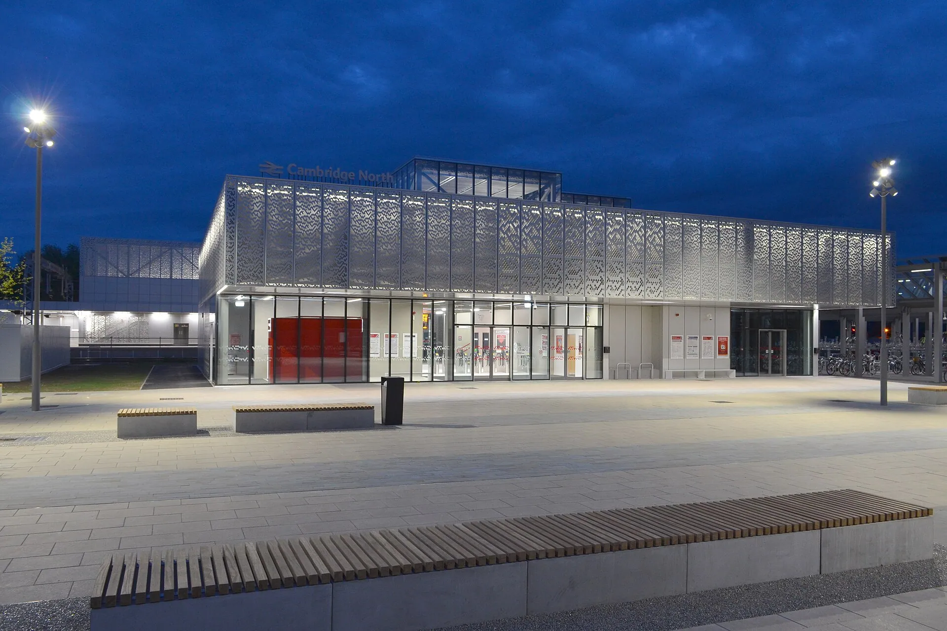 The glazed frontage of Cambridge North railway station, England, lit at dusk